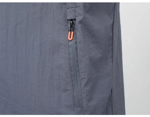 Detail of grey sun protection jacket showing water-resistant fabric and orange zipper pull