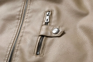 Vue détaillée de la texture en cuir PU marron avec fermeture éclair et bouton pression argent