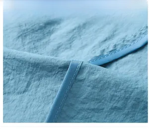 Vue détaillée du tissu bleu clair montrant la finition précise des coutures de bordure