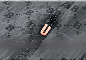 Detail of gray sun-protective jacket showing B-pattern print and orange zipper puller