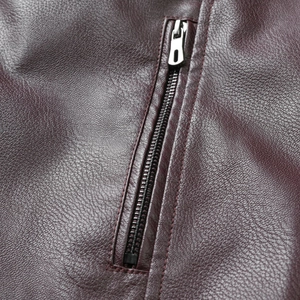 Vue macro de la fermeture éclair argentée sur une veste en cuir bordeaux texturé