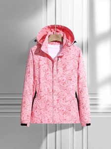 Women's pink hooded windbreaker jacket with tropical leaf print hanging on white wall