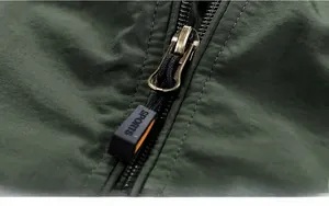 Macro detail of bronze metal zipper and green waterproof fabric on men's winter parka
