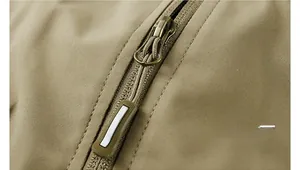 Détail macro de la fermeture éclair en métal et tissu kaki sur le gilet d'extérieur