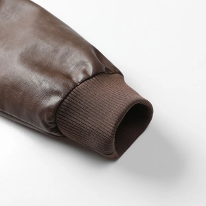 Détail macro des poignets en maille côtelée d'une veste en similicuir marron texturé