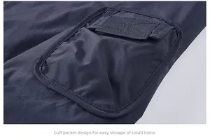 Detail of navy blue jacket sleeve with a utility pocket and Velcro flap closure