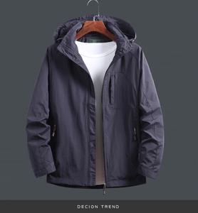 Detail of navy blue windbreaker with hood, vertical chest zipper, and high-quality fabric