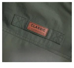 Detail der militärgrünen Outdoorjacke mit braunem Classic 1901 Lederpatch auf dem Stoff