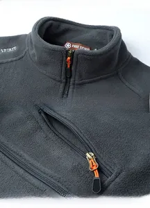 Detail of high collar and zippered pocket with orange pull on dark grey fleece vest