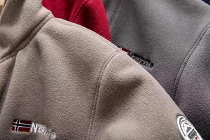 Close-up of thick fleece jacket texture featuring embroidered Norway flag and badge