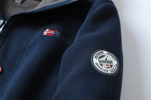 Detail of navy fleece jacket featuring Norway flag embroidery and outdoor mountain badge