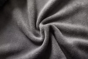 Macro texture of thick dark grey polar fleece fabric showing warm soft plush material