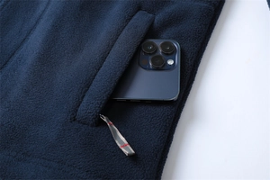 Detail of dark blue fleece jacket showing a side pocket with phone for size reference