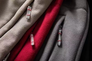 Detailed macro view of fleece jackets featuring zipper pockets with red contrast drawstring cords