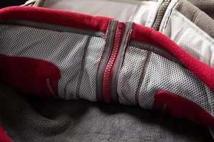 Detail of outdoor fleece jacket showing gray mesh lining and red resin zipper closure