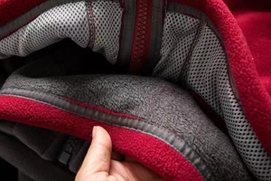 Close-up of deep red fleece jacket with grey mesh lining and premium zip detail