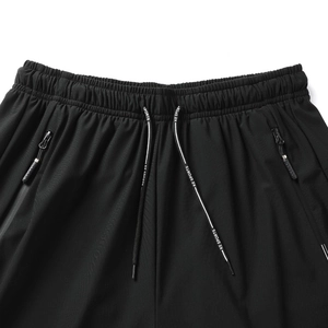 Detail view of black quick-dry shorts featuring elastic waistband and branded drawstring