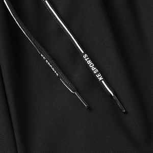 Macro shot of black sport trousers showing fabric texture and KE SPORTS logo drawstrings