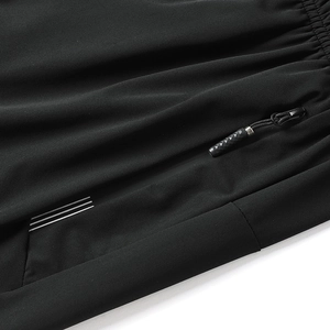 Close-up of black breathable pants with reflective stripes and hidden zipper pocket