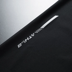 Close-up of black breathable ice silk fabric with silver ATHLE lettering and sport texture