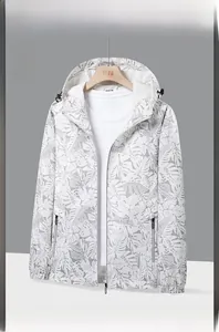 Détail d'une veste blanche imperméable avec motifs de feuilles de monstera et capuche