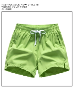 Detail of green athletic shorts featuring white drawstring waist and breathable side slits
