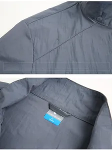 Détails du coupe-vent gris-bleu montrant le col montant et l'impression sur l'épaule