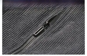 Macro detail of dark grey corduroy fabric texture and durable black metal zipper