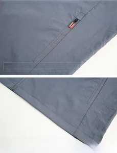 Détail veste gris bleu avec tirette orange en U et ourlet à double couture de précision