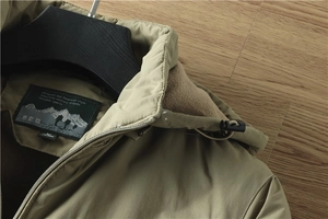 Detailweergave van de kraag van de kaki tactische jas met geborduurd logo en het label