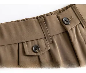 Detail view of brown shorts featuring a semi-elastic waistband with a stylish tortoise button