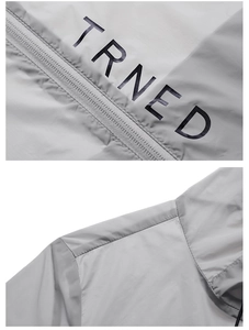 Détail de la veste légère grise avec fermeture éclair fluide et imprimé logo TRNED