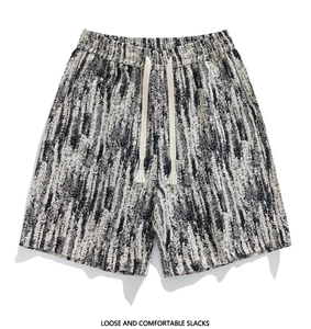 Detail of loose men's shorts featuring abstract black and white print with tasseled drawstring