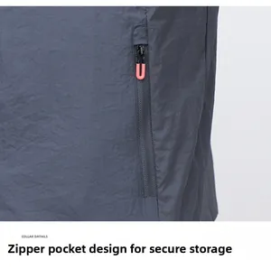 Detail of gray sun-protective jacket showing zippered pocket with orange puller
