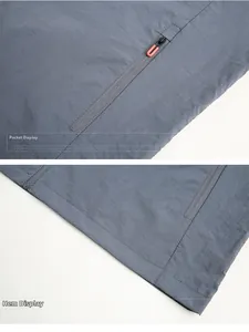 Detail of dark gray outdoor jacket showing zipper side pocket and hem craftsmanship