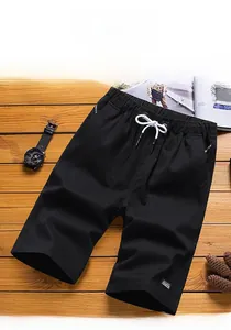 Flat lay of black men's cotton shorts with white drawstring and elastic waist on wood