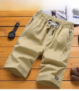 Detail of khaki cotton shorts featuring elastic drawstring waist on wooden floor
