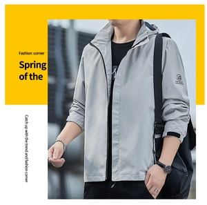 Détail du poignet d'une veste gris clair avec patte de serrage velcro noire et logo