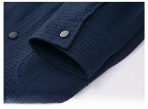Detail view of navy blue waffle texture fabric and black snap button on the jacket cuff