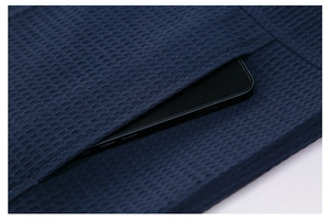Detailed close-up of a waffle-knit navy jacket pocket holding a smartphone for scale