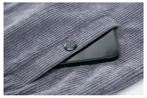 Detail view of grey corduroy jacket fabric texture and pocket with a black button