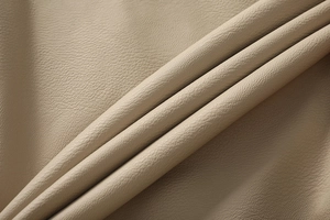Close-up of premium beige faux leather fabric showing soft texture and litchi grain detail