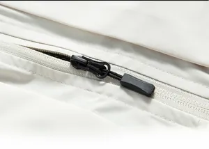 Détail de la fermeture éclair en nylon sur une veste de pêche beige avec tirette antidérapante