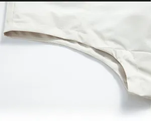 Vue macro détaillée de l'emmanchure du gilet blanc crème montrant le tissu lisse et les coutures