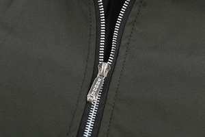 Macro view of metallic zipper with VOGUE engraving on a green flight jacket