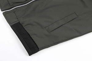 Detail of olive bomber jacket showing silver zipper, slanted pocket and ribbed knit hem