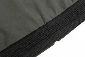 Macro view of olive green jacket fabric with black ribbed hem and silver metal zipper detail