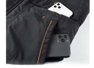 Detail shot of men's winter jacket showing large pockets with mobile phones for scale