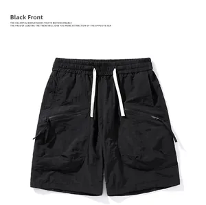 Detail of black quick-dry shorts featuring elastic drawstring waist and zippered pockets