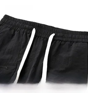 Detail of elastic waist with white drawstring and zipper pocket on black quick-dry shorts
